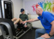 Man sport in de oefenzaal na het oplopen van beenblessures en wordt geholpen door fysiotherapeit siko van actifytaal