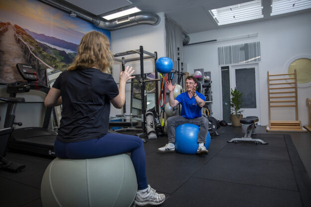 Fysiotherapeut helpt vrouw met bewegen, zodat ze niet te hard van start gaat met sporten en krijgt sportfysiotherapie.