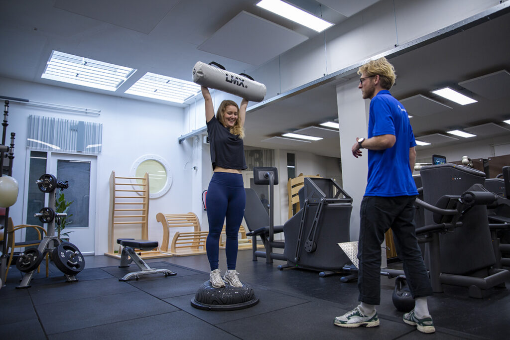 Fysiotherapeut helpt een vrouw in zwarte sportkleding met sporten voor een positievere mindset.