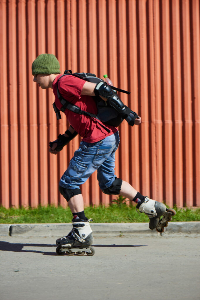 Man in rood t-shirt skeelert met heel veel bescherming aan. Hij doet dit omdat hij last had van blessures door het skeeleren.