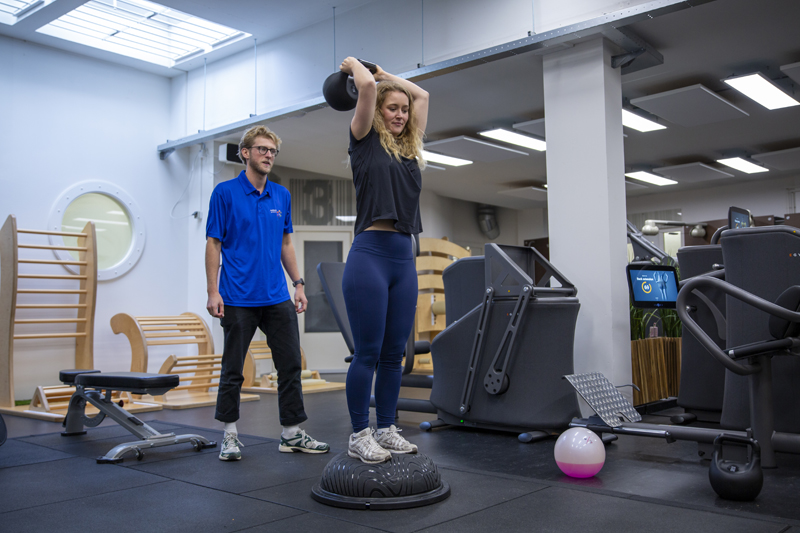 blessures in de sportschool Fysiotherapeut helpt vrouw met bewegen tegen blessures in de sportschool.