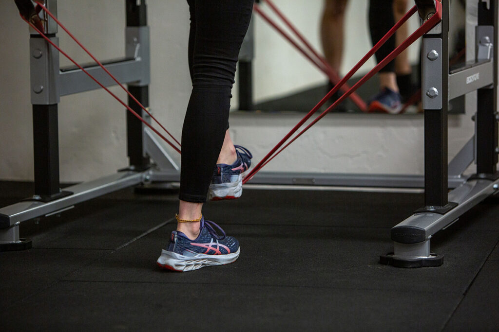 Vrouwelijke sporter doet een oefening in de sportzaal om achillespeesklachten na sporten te voorkomen