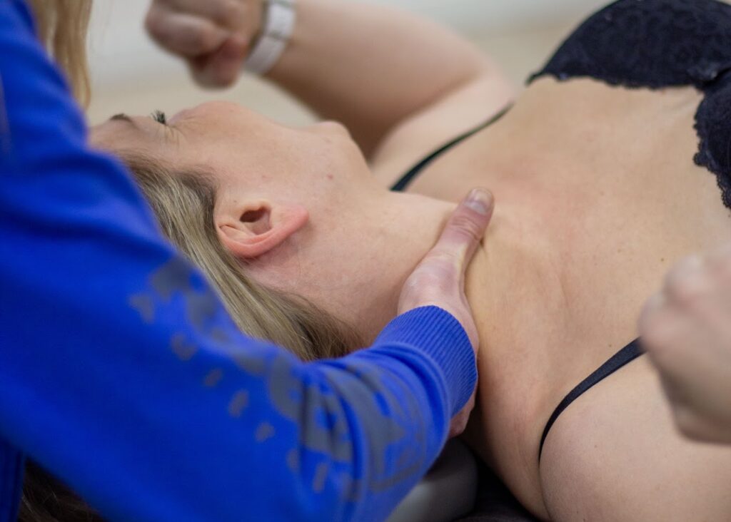 Vrouw komt met een stijve nek bij het opstaan bij de fysiotherapeut en wordt geholpen op de behandelbank